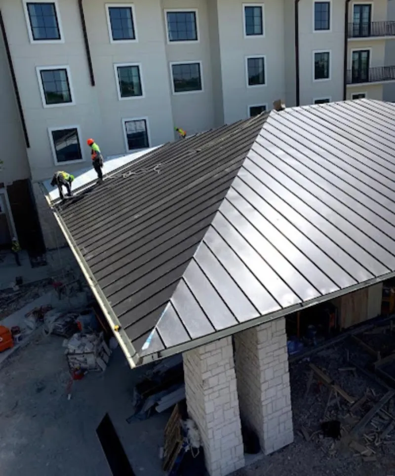 Crew installing standing seam metal roof panels on a commercial project in Lake Charles